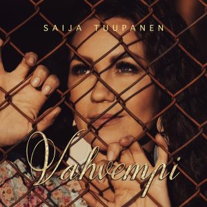 Saija Tuupanen Vahvempi25cds Media Vahvempi-siglen kannessa Saija Tuupanen katsoo verkkoaidan takaa mietteliäänä.